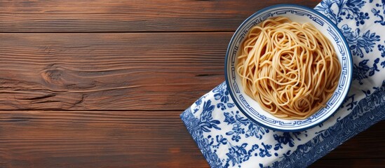 Aufkleber - A top down view of a plate of noodles on a wooden table accompanied by wooden chopsticks set against a blue and white towel Perfect for copy space image