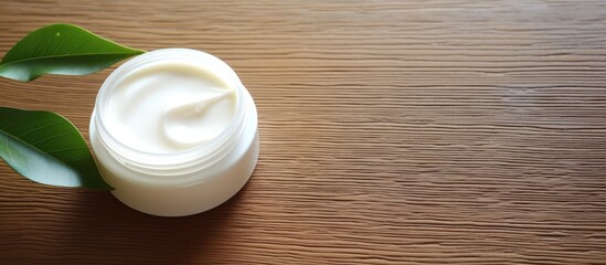 Poster - On a bright wooden table there is a white cosmetic cream with leaf buds in the background creating a visually appealing image with empty space. Creative banner. Copyspace image