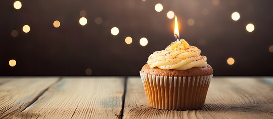 Wall Mural - A wooden background sets the stage for a festive anniversary celebration complete with a muffin adorned with a burning candle The postcard carries heartfelt birthday wishes highlighted by candle lett