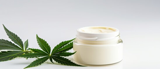 Poster - A flat composition on a white background displays a jar with CBD infused moisturizing body cream made from natural products surrounded by green cannabis leaves There is copy space available in the im