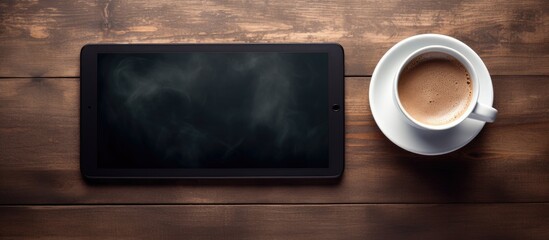 Fototapete - From above an aerial shot captures a Tablet PC accompanied by a steaming cup of coffee creating a visually pleasing composition with ample space for copy