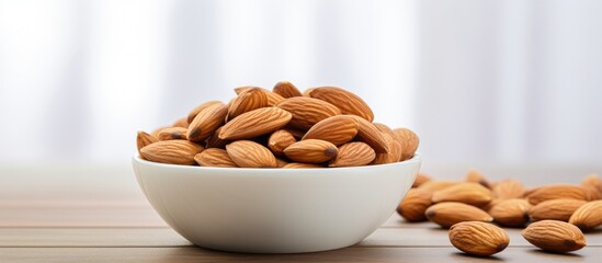 Aufkleber - A close up image of a delicious and healthy almond snack displayed in a white ceramic bowl placed on a white wooden background with ample space for text