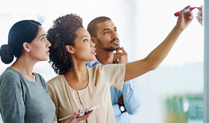 Poster - Business people, writing and thinking with tablet for planning, tasks or agenda on glass board at office. Group of young and creative employees taking notes for discussion, brainstorming or startup