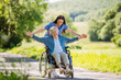 © Halfpoint - Female caregiver pushing senior woman in wheelchair. Nurse and elderly woman enjoying a warm day in nursing home, public park.