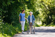© Halfpoint - Female caregiver and senior woman with walker on walk in nature. Nurse and elderly woman enjoying a warm day in nursing home, public park.