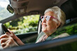 © Halfpoint - Happy senior woman driving car alone, enjoying car ride. Safe driving for elderly adults, older driver safety.