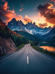 Canvas Print - Empty highway on the background of mountain peaks in the Italian Alps, a lake in a gorge, sky illuminated by the sun rays at sunset