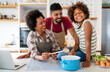© NDABCREATIVITY - Happy african american family preparing healthy food in kitchen, having fun together on weekend