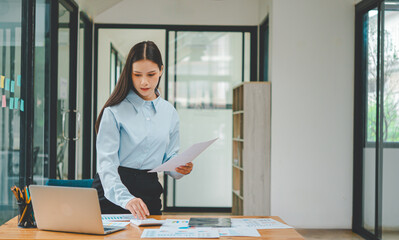 Wall Mural - Asian business woman working using laptop for do math finance on wooden desk, tax, accounting, statistics and analytical research concept