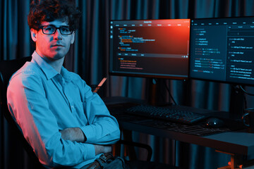 working it developer looking at camera with online software development information at neon light ro