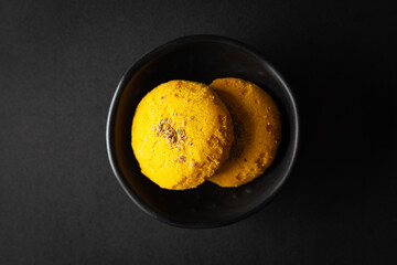 Wall Mural - pieces of  Yellow cookies placed in a black bowl on a black background.