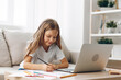 © SHOTPRIME STUDIO - Young girl sitting on couch with laptop and pencil, engaged in online learning or creative work