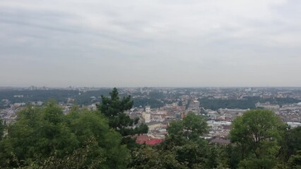 Wall Mural - A city view with a cloudy sky and trees in the background