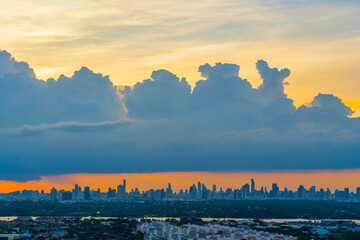 Wall Mural - Sunrise over modern buildings in district center. Heavy cumulus before storm weather city silhouette skyscrapers sunset sky Panoramic skyline view cityscape with sunlight flare warm light color tone