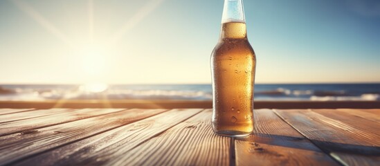 Poster - Opened bottle of beer with condensation on the wooden table Blurred sparkling sea at the background Summer vibes. Creative banner. Copyspace image