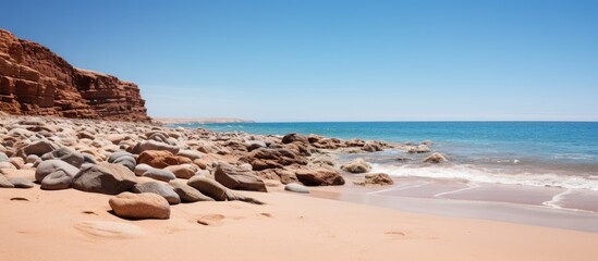 Poster - view of brown rocks on the beach with a beach and blue sky. Creative banner. Copyspace image