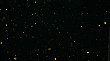 Small gold molecules glowing underwater, dark background, slowmo