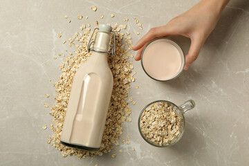 Wall Mural - Bottle and glass with milk, oatmeal and hand on beige background, top view