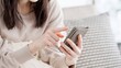 © mapo - リビングでスマホを見る女性