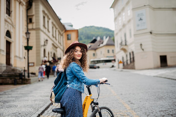 Female traveller on electric scooter in small city, sightseeing. Young tourist using bike during her summer solo trip, vacation.