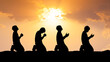 © STOCK PHOTO 4 U - Silhouetted Figures Praying at Sunset with Dramatic Sky and Sunlight in the Background, Capturing Spirituality, Devotion, and Peaceful Reflection in a Serene Outdoor Setting
