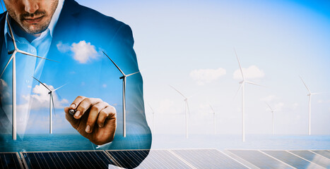 Wall Mural - Double exposure graphic of business people working over wind turbine farm and green renewable energy worker interface. Concept of sustainability development by alternative energy. uds