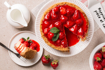 Wall Mural - Classic baked Cheesecake  with a strawberry topping sauce directly above. Cake server where is written Happiness is the piece of cake.