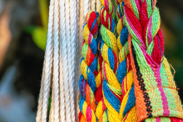 Wall Mural - Colorful cotton rope. Thick cotton rope showing detail of threads and fibres. Yarn braid rope of cradle. Multicolored yarn has been braided into a braid. Knitted fabric background. Selective focus.