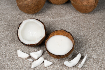 Wall Mural - Coconut milk in coconut shell and half coconut, chopped flesh on grey background