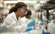 © Curioso.Photography - A young female scientist carefully pipetting liquid into test tubes in a laboratory setting.