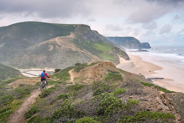 Wall Mural - happy active senior woman cycling on the the rocky cliffs of the Vicentina coast of  Algarve, Portugal near Sagres and Vila do Bispo 