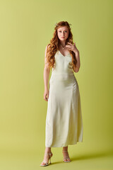 Wall Mural - A young woman in a white wedding dress poses gracefully against a green background.