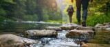 Hikers crossing a clear, bright river with stepping stones, surrounded by nature, minimalistic shapes with space for text