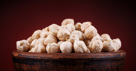 Wall Mural - Clay cup with chickpeas on a beautiful illuminated red background.