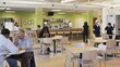 © Felippe Lopes - People dining and socializing in a modern cafeteria with colorful walls and various seating options