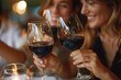 © Lens Legacy - Close-up of two women toasting with glasses of red wine, symbolizing celebration and friendship