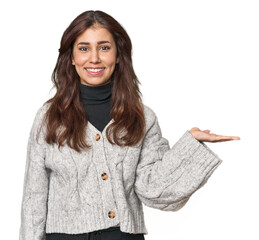 Wall Mural - Middle Eastern woman in studio showing a copy space on a palm and holding another hand on waist.