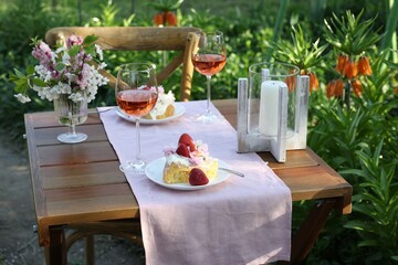 Canvas Print - Vase with spring flowers, wine and cake on table served for romantic date in garden