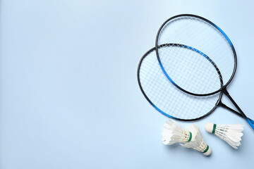 Wall Mural - Feather badminton shuttlecocks and rackets on light blue background, flat lay. Space for text