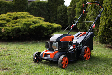 Wall Mural - Modern lawn mower on green grass in garden