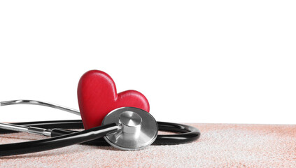 Stethoscope and red heart on color textured table against white background, space for text