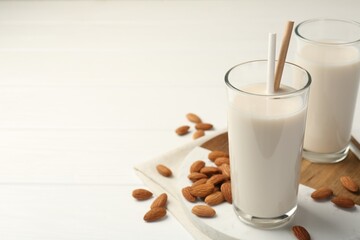 Wall Mural - Glasses of almond milk and almonds on white wooden table, space for text