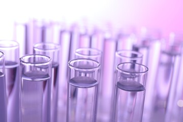 Many glass test tubes on violet background, closeup