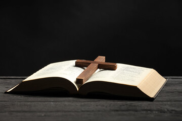 Wall Mural - Bible and cross on gray wooden table against dark background, space for text. Religion of Christianity