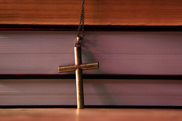 Wall Mural - Cross and stack of books on table, closeup. Religion of Christianity