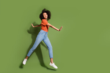 Poster - Full size photo of pretty young girl running jump wear trendy orange outfit isolated on khaki color background