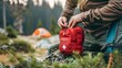 © Ziyan Yang - High-quality photo of a male hand taking a first aid kit out of a backpack pocket, featuring camping equipment and a compact mini first aid kit