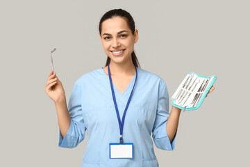 Poster - Portrait of female dentist with set of dental tools on grey background