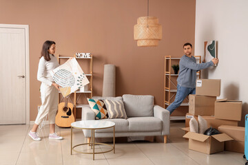 Wall Mural - Happy young couple with paintings in room on moving day