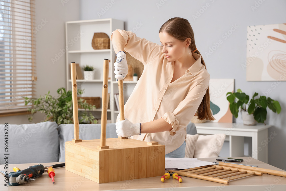 Beautiful young woman assembling wooden table at home